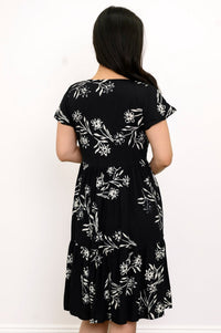 Back view of woman with her hair pushed to the side and wearing a short-sleeve black dress with white flowers on it