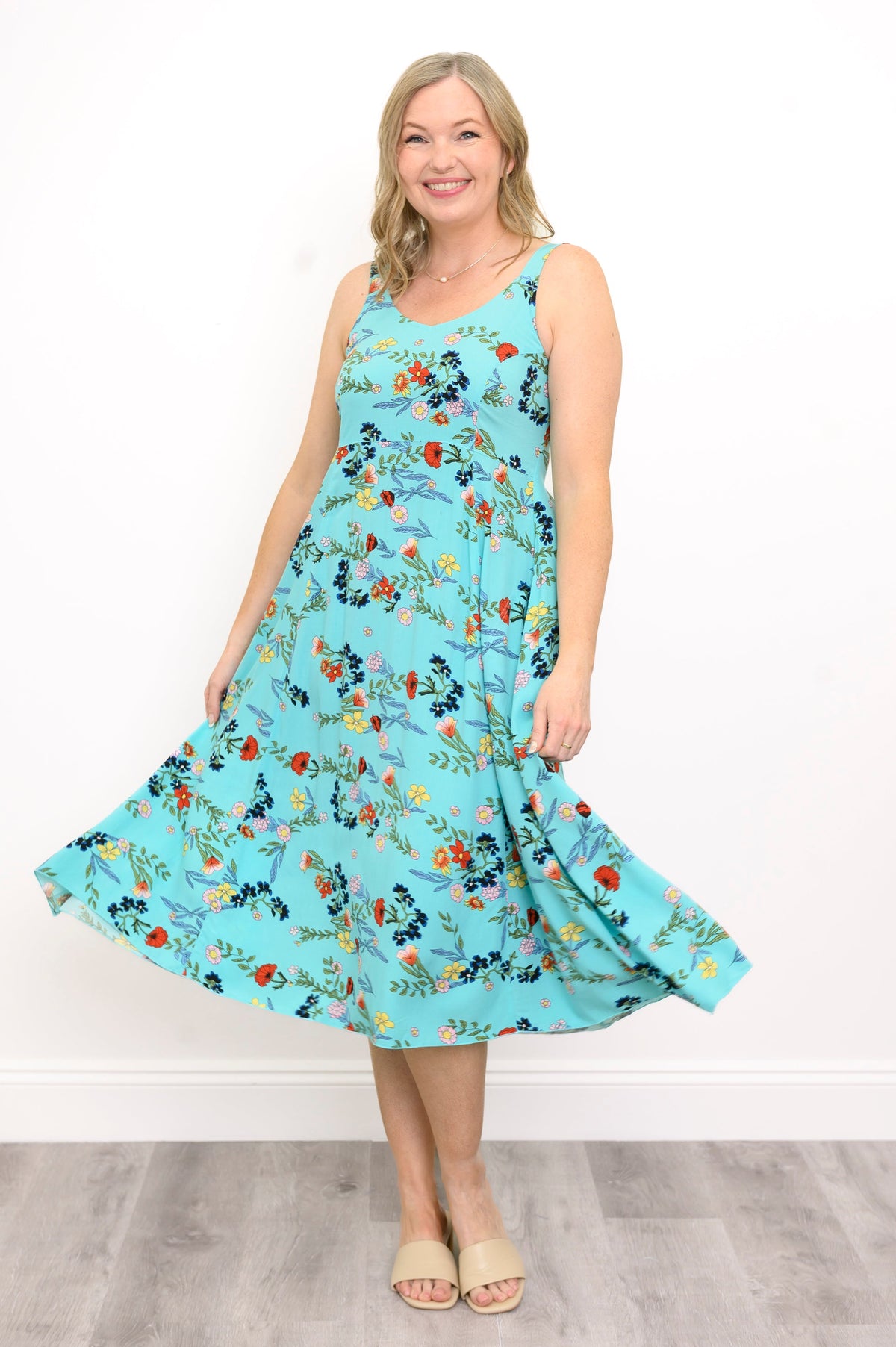 Woman wearing a blue floral dress against a white background, front view