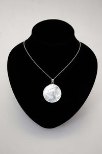 Sterling silver shell pendant necklace displayed on a black necklace bust