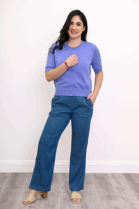 Woman smiling in a purple Shen cardigan, left hand touching chest
