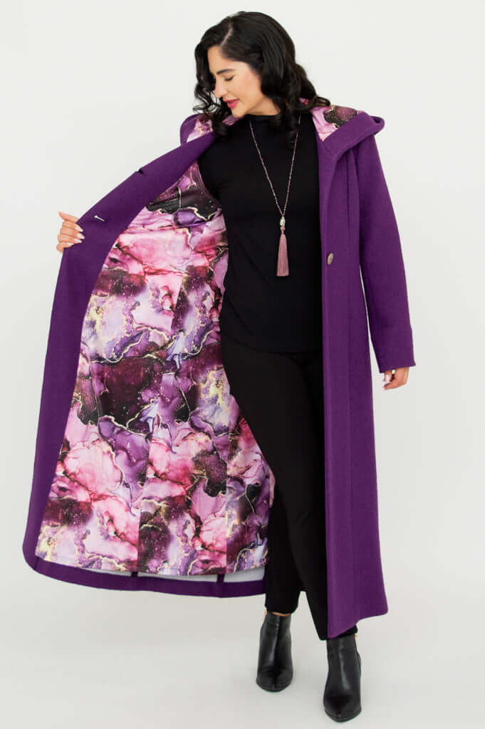 Woman showing the vibrant patterned lining of a purple hooded coat