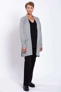 Side-angled view of a woman in a grey open cardigan styled with black pants