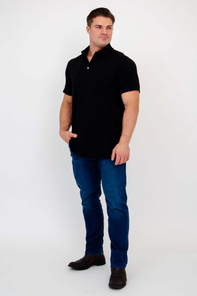 Man in black bamboo polo shirt and blue jeans looking to the side