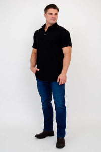 Man in black bamboo polo shirt and blue jeans looking to the side