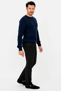 Man in navy sweater and black pants turned slightly to the side