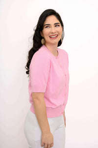 Woman smiling in a pink cropped cardigan viewed from the side