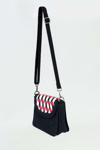Side angle of black crossbody bag with geometric red, white, and black pattern