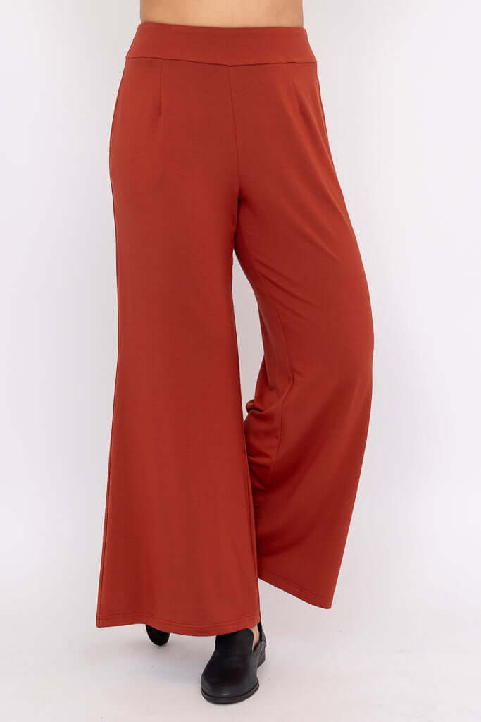 Side angle of rust wide leg pants with wide-leg silhouette and black shoes