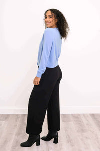 Side view of a woman showing the fit of a blue cashmere cardigan and black pants