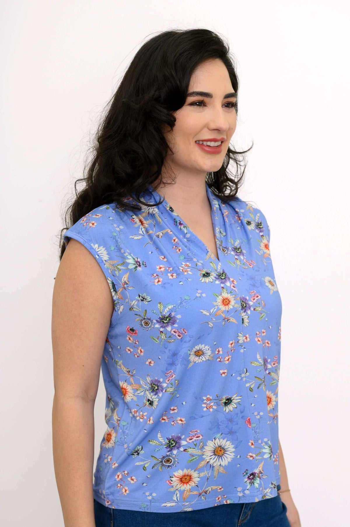 Side view of a woman in a blue floral sleeveless top with shoulder pleats