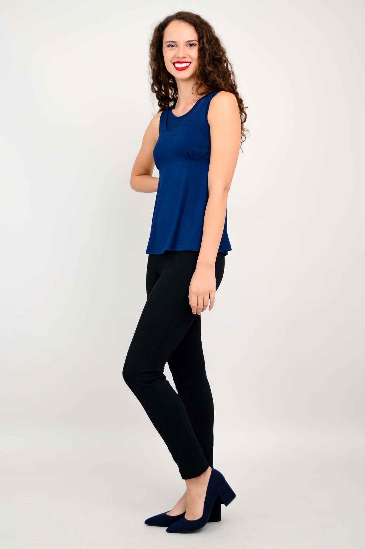 Side view of woman in fitted navy bamboo tank top with mesh detail and black pants
