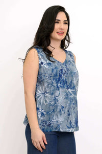 Side view of woman in blue botanical sleeveless V-neck blouse with dark jeans
