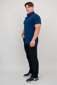 Side view of man wearing navy bamboo polo shirt and black pants
