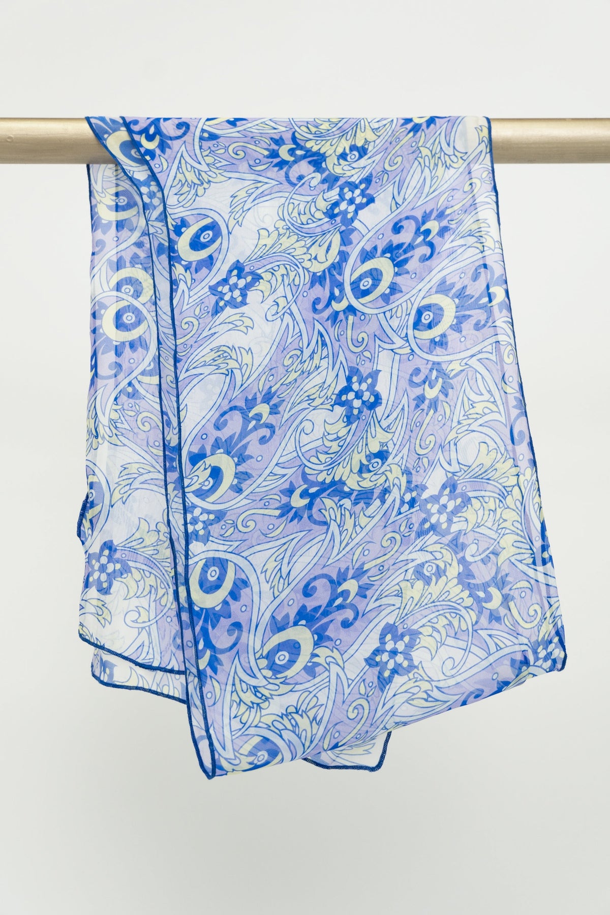 A large silk scarf with a blue and white paisley pattern displayed on a rod, front view