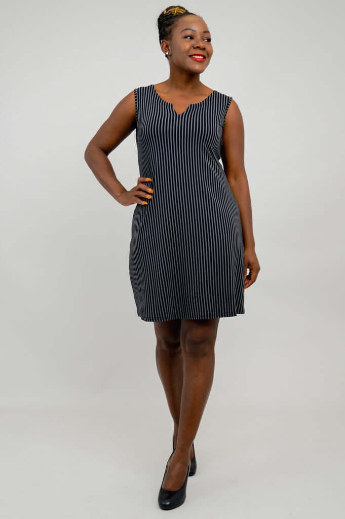 Woman smiling and looking sideways in a sleeveless striped black and white shift dress
