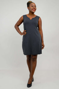 Woman smiling and looking sideways in a sleeveless striped black and white shift dress