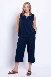Woman smiling in a navy sleeveless top and matching linen capri pants