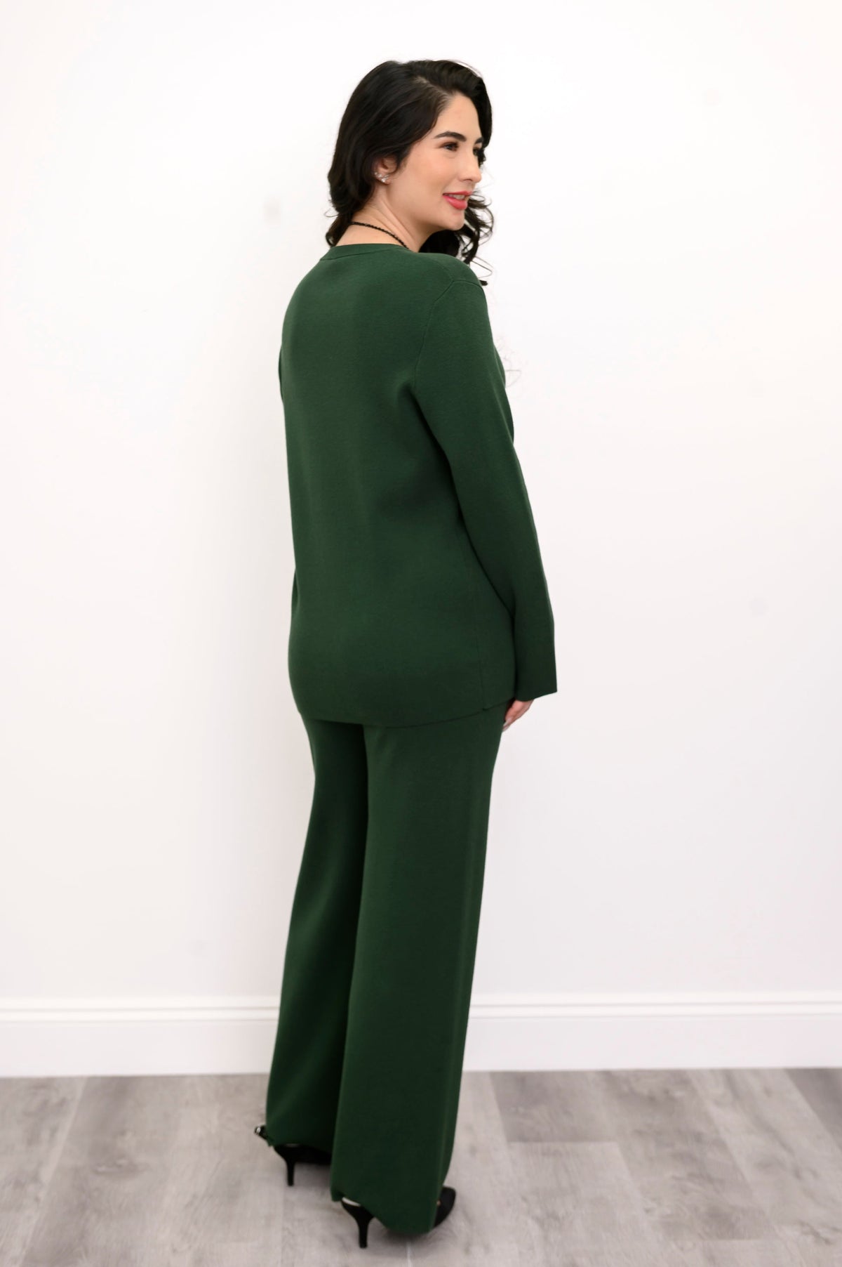 Rear view of a forest-green knit tunic on a model, highlighting its comfortable, seat-covering length.