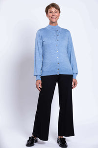 Woman standing in blue cardigan and black pants with black shoes
