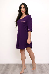 Woman angled slightly and modeling a knee-length purple nightgown and pink trim