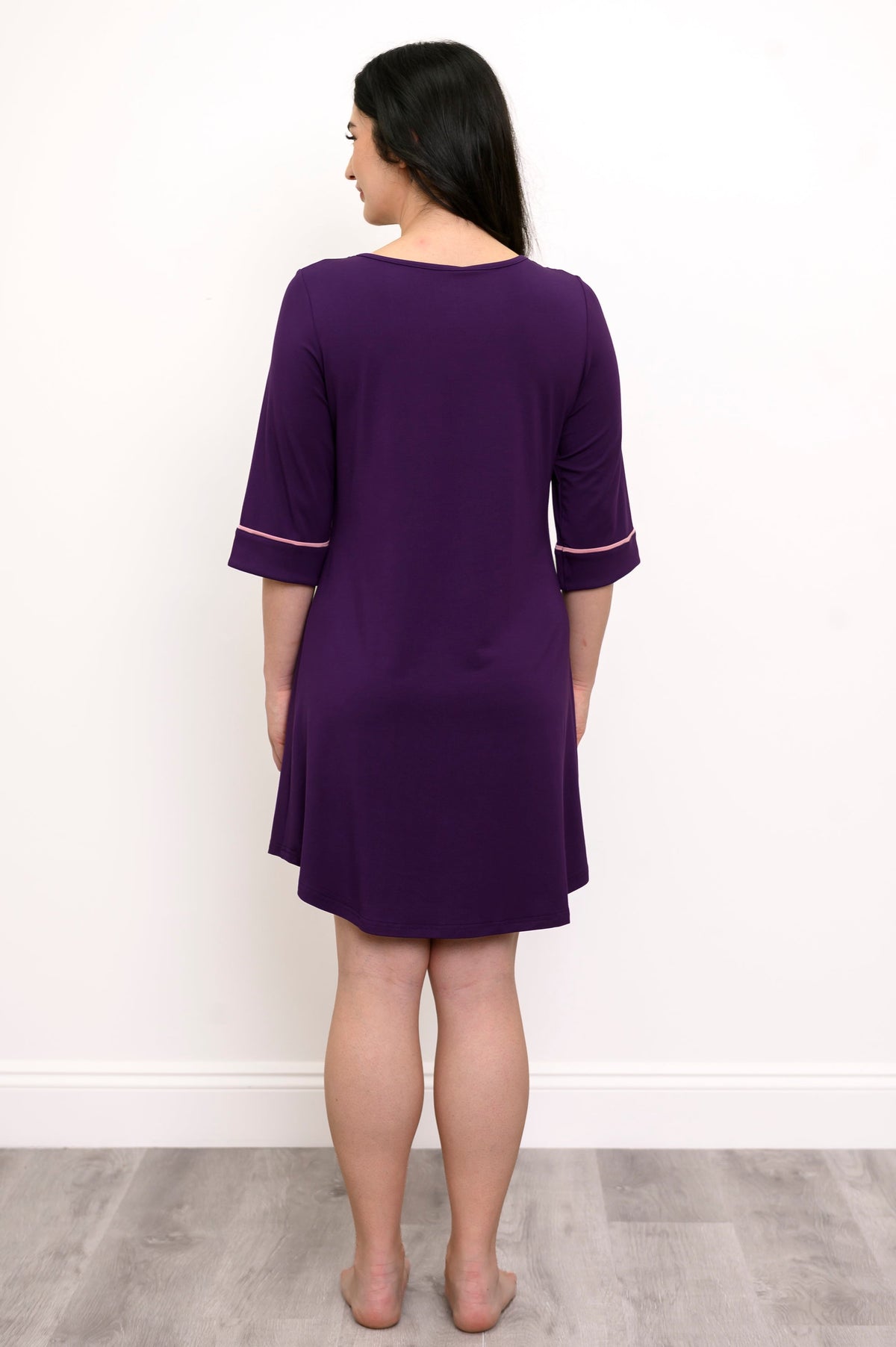 Back view of woman wearing a purple sleep dress with pink trim against a white background