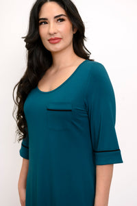 Close up view of woman smiling and looking off center as she wears a half-sleeve teal colored sleep dress