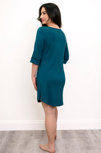 Back view of woman wearing a knee-length teal nightgown with black trim against a white background