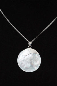 Close-up of a sterling silver necklace with a round polished shell pendant on black background