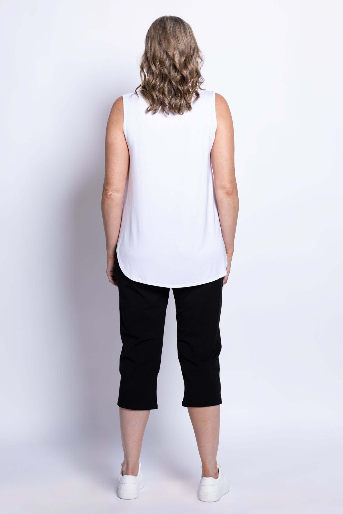 Model showing back view of Susan Capri pants with white tank top