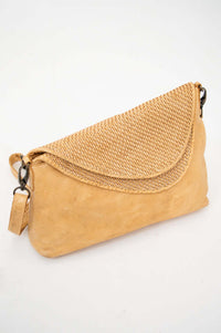 Tan leather crossbody bag with woven flap on white background