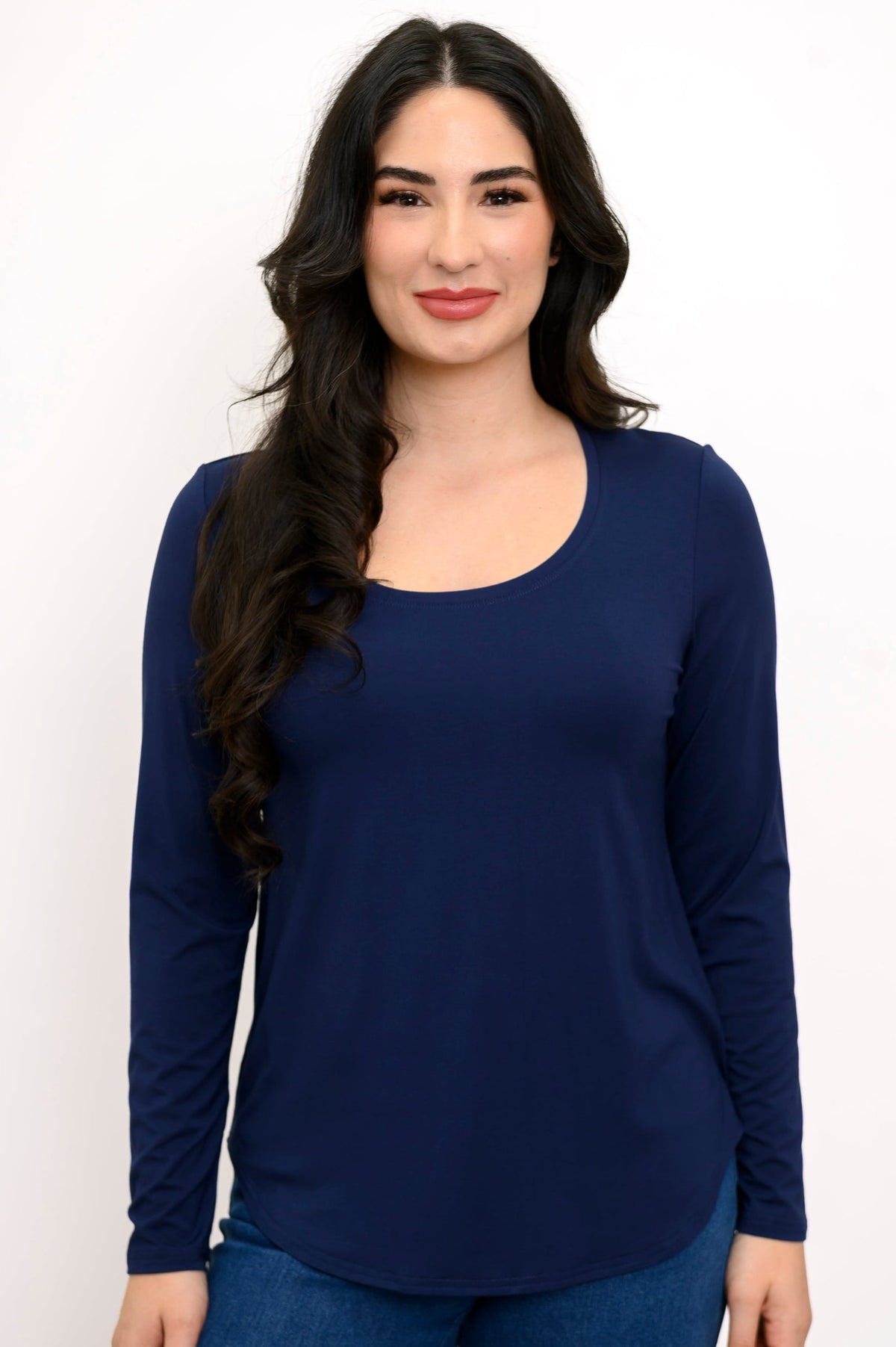 Close up front view of woman wearing a navy blue long sleeve shirt and denim pants on a white background