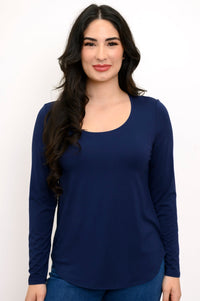 Close up front view of woman wearing a navy blue long sleeve shirt and denim pants on a white background