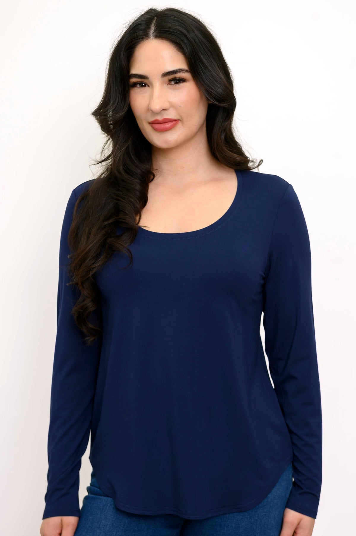Close up front view of model wearing a round-neck full-length dark blue top and denim pants