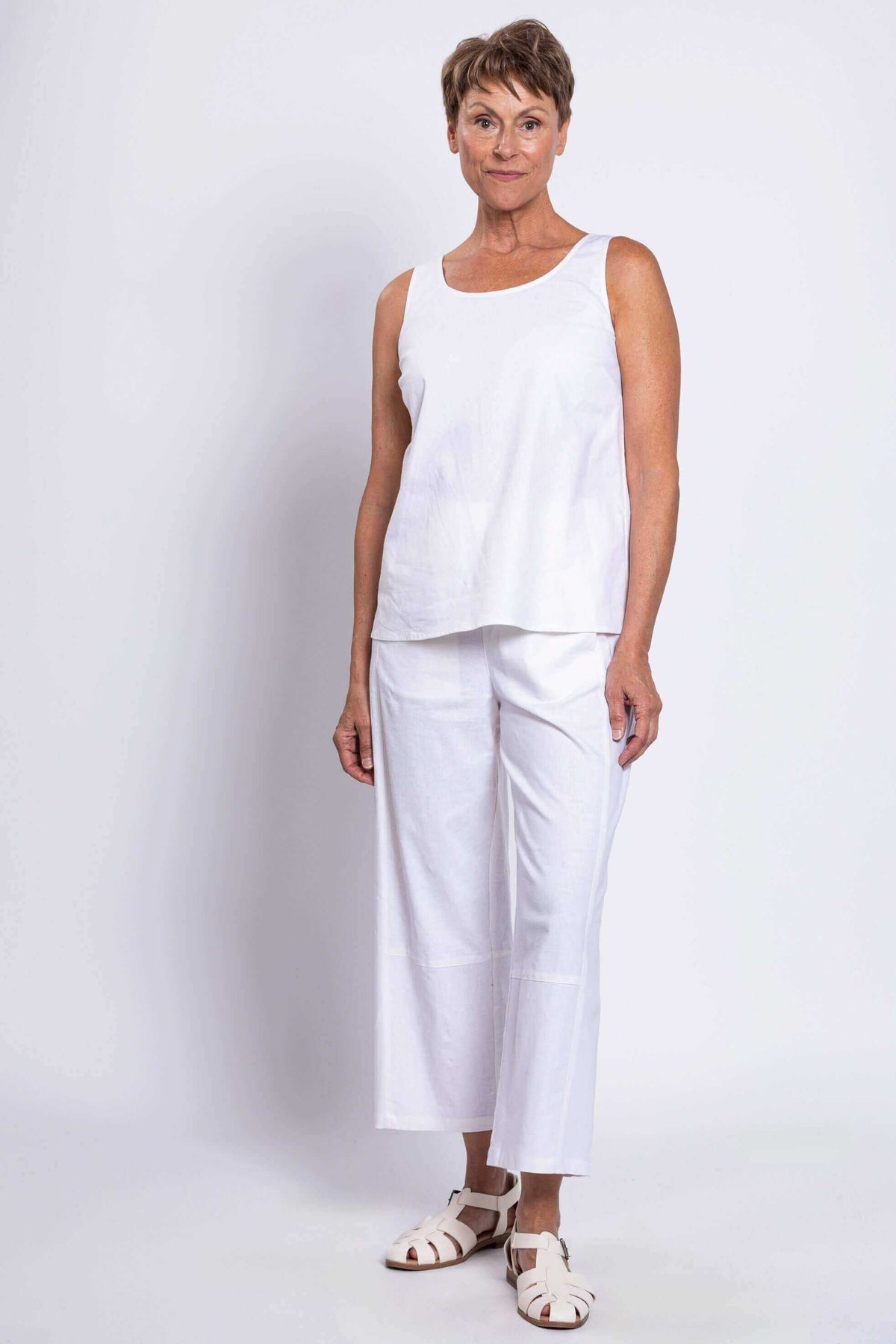 Three-quarter front view of woman in white linen tank top and pants
