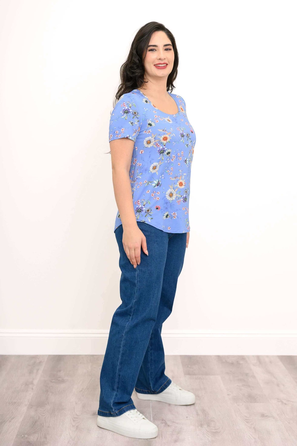 Woman in blue floral tee posing at a three-quarter angle