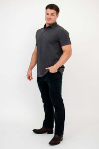 Three-quarter side view of man in dark grey bamboo polo shirt and black jeans