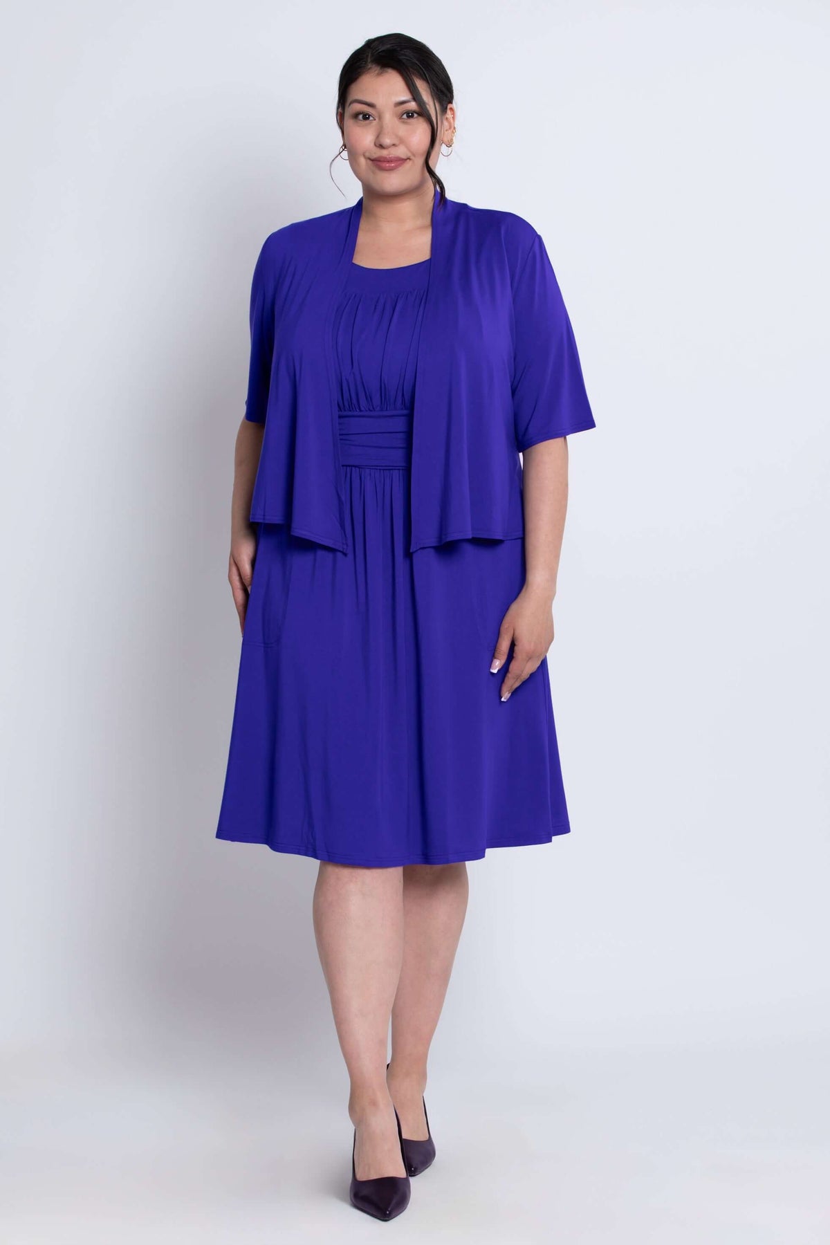 Three-quarter view of model wearing cobalt blue cropped jacket and dress ensemble