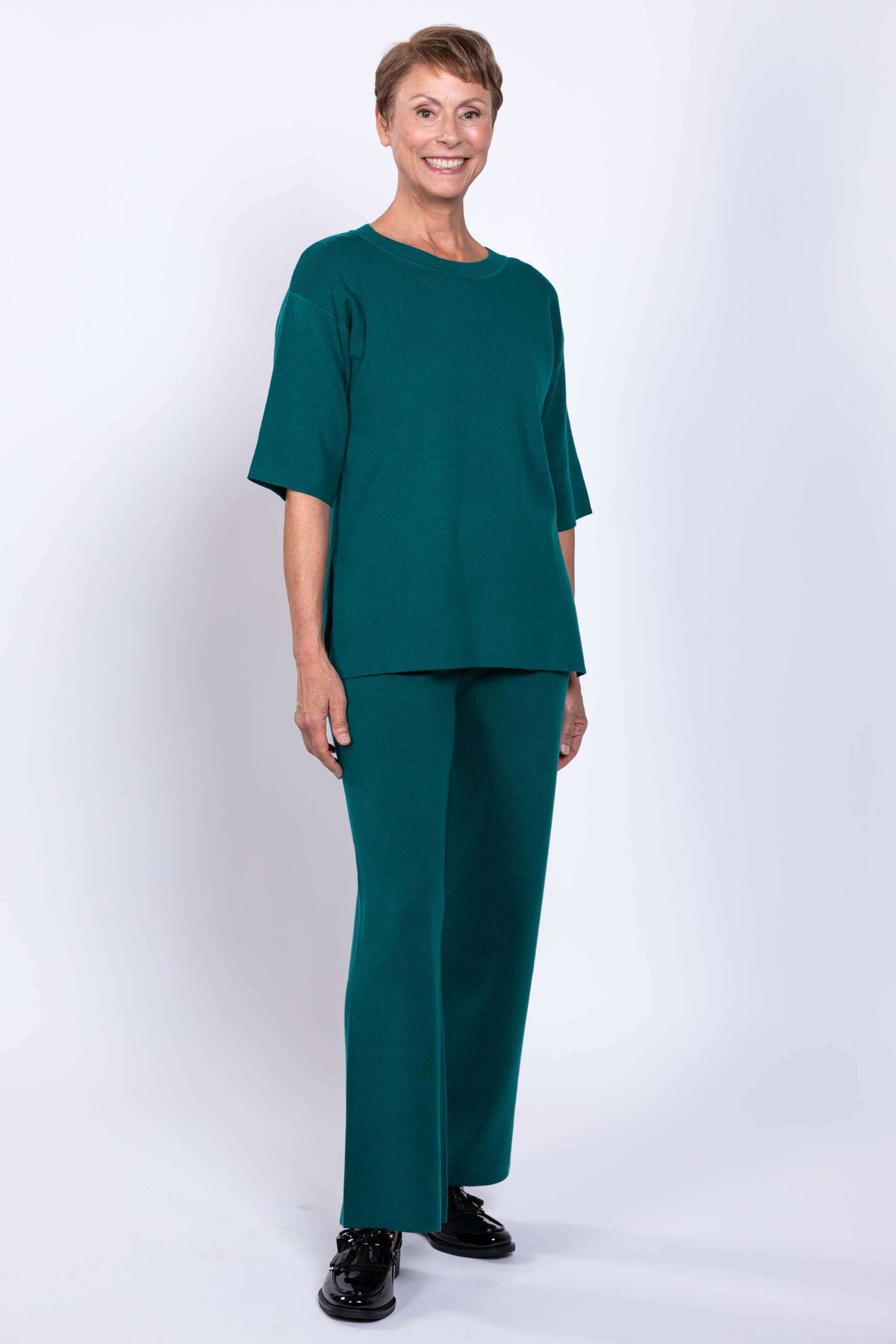 Front view of a model wearing a teal relaxed fit short sleeve knit top paired with matching trousers.