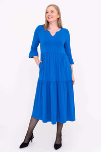 Three-quarter view of a woman in a blue long dress with ruffle sleeve and tiered skirt