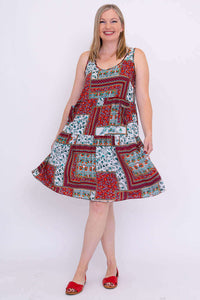 Woman twirling in a sleeveless, tiered patchwork dress with a flowing skirt