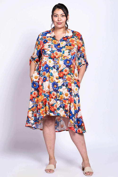 Model wearing a vibrant floral shirt dress with ruffled hem and high-low cut