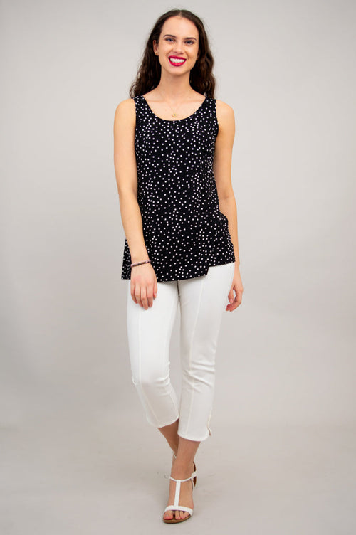 Women's black sleeveless top with white polka dots, round neckline, relaxed fit, and hip-length cut styled with white pants