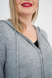Close-up shot of woman wearing a grey zip-up sweater on a black top and wearing red lipstick