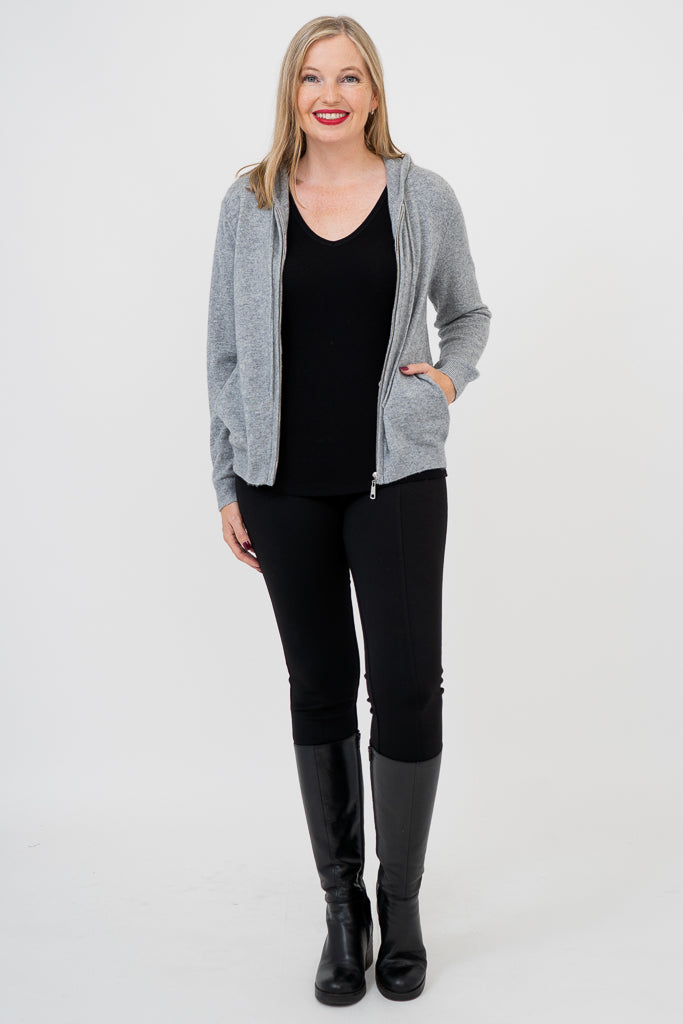 Woman wearing grey knit sweater on a black outfit against a white background, front view