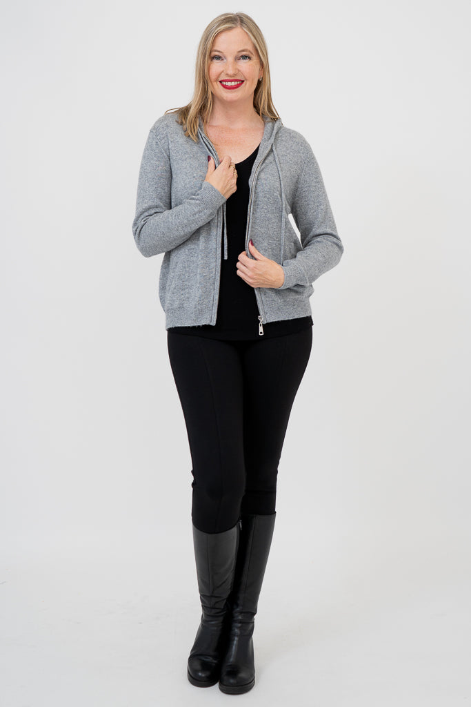 Woman wearing grey knit sweater on a black outfit against a white background, front view