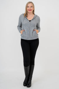 Front view of woman wearing a grey sweater, black pants, and black boots against a white background