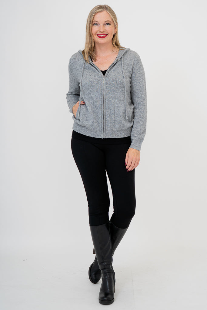 Woman wearing grey knit sweater on a black outfit against a white background, front view