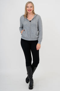 Woman wearing grey knit sweater on a black outfit against a white background, front view