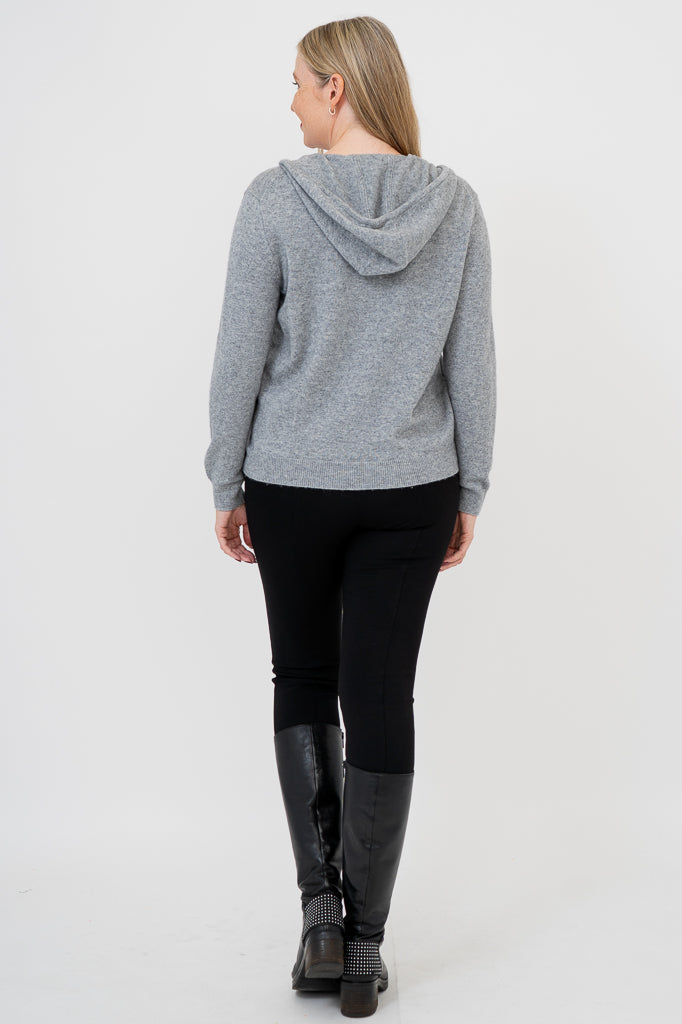 Woman wearing grey knit sweater on a black outfit against a white background, back view