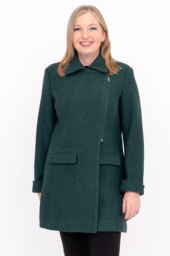 Woman wearing green collared wool coat with pockets and a zipper paired with black pants against a white background